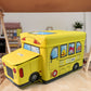 School Bus Toy Storage Box by Dollamis, partially open, showcasing its vibrant design.