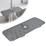 CrystalWash silicone faucet mat in dark grey, shown protecting a kitchen sink countertop from water splashes.