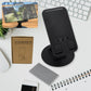 A sleek black rotating mobile stand, folded compactly on a desk, ready for use.