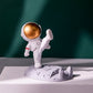 Astronaut Phone Holder (kicking leg design) on a wooden desk, holding a smartphone.