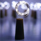An illuminated wine bottle cork string light creating a warm ambiance on a wooden surface.