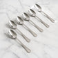 Set of 6 stainless steel dining spoons with polished finish on dining table