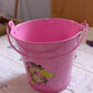 Metal planter bucket serving as a charming flower pot on a patio table.