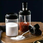 Transparent glass jar with built-in spoon for easy kitchen access to spices