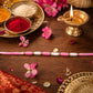 Close-up of Pink & White Thread Rakhi with golden beads