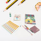 Vibrant cartoon stationery box with a notebook, pen, and eraser for school kids.