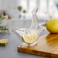 Hand holding the unique bird-shaped manual juicer over a glass.