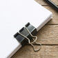 Office binder clips in black with silver handles holding documents