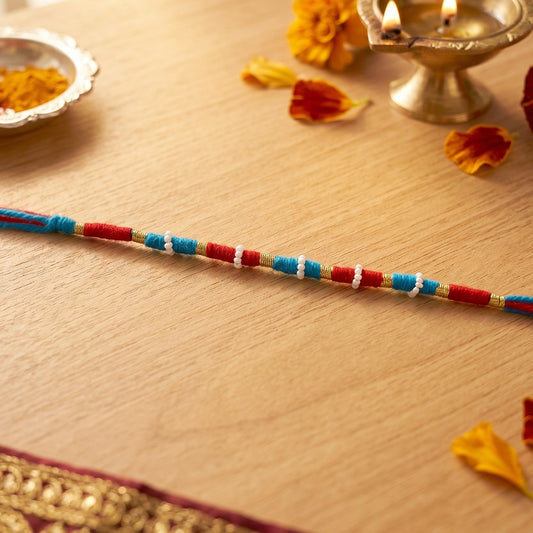 Traditional red rakhi with pearl and gold bead decorations