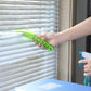 A person using the window blind cleaner brush with microfiber sleeves to dust white window blinds.