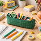 Colorful pens and pencils organized in the green grid stationery pouch.