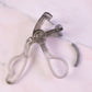 Transparent eyelash curler viewed from side angle showing smooth press