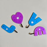 Love shape self adhesive hooks in white, mounted on a wall.