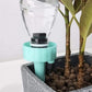 A self-watering spike inserted into a potted plant, demonstrating its discreet and effective use.