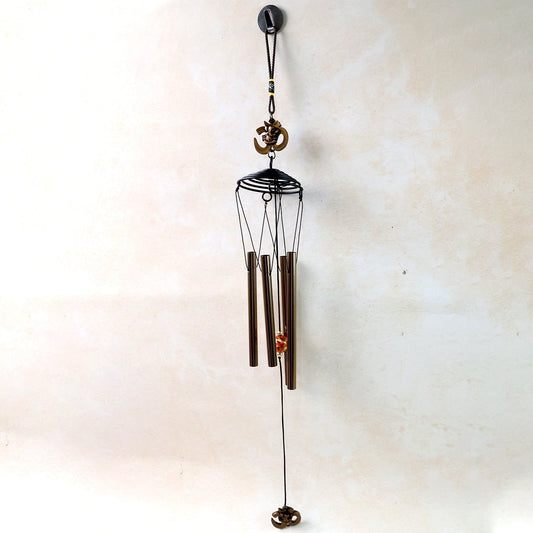 Metal Om symbol wind chime hanging on a wooden porch