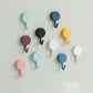 Pack of 10 transparent self-adhesive wall hooks on a white surface.