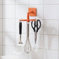 Orange rotating kitchen utensils hook stand mounted on kitchen wall
