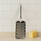 Flat handheld stainless steel vegetable grater in use grating carrots