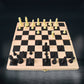 Detail of the wooden chess board's smooth surface and inlaid squares.