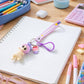 Bag accessory keychain with doll and cupcake charm on rainbow strap