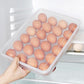 Hand pulling out a clear 24-grid plastic egg container from fridge shelf