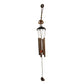 Side view of metal wind chime with Om symbol against green background