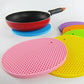 A red silicone hot pot mat being rinsed under water, illustrating its easy-clean feature.