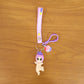 Detailed close-up of doll and cupcake charms on colorful rainbow strap keychain