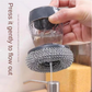 Close-up of the soap dispenser with scrub button, showing soap being dispensed onto a sponge.