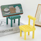 Gambit Mini Chair Phone Stand in natural wood, holding a smartphone upright on a desk.