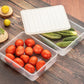 A transparent plastic vegetable storage box with a blue lid, shown filled with various fresh vegetables.