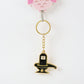 Golden Shivling keychain displayed on white surface showing metal craftsmanship