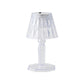 A compact crystal table lamp reflecting light onto a wall.