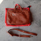 Faux leather messenger bag open with a laptop and other daily essentials neatly arranged inside.