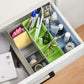 Clear plastic organizer box with sections holding colourful beads and craft supplies.