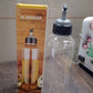 Hand holding the clear 1L oil dispenser, demonstrating its easy-pour function.