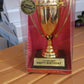 Front view of golden birthday trophy with printed label on sturdy base