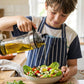 Pouring action with glass oil bottle in kitchen