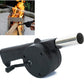 Man using a hand-cranked charcoal grill fan to ignite BBQ coals outdoors.