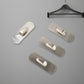 Two stainless steel self-adhesive hooks neatly holding towels in a modern bathroom.