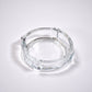 Clear glass ashtray featuring a classic round shape and convenient cigarette slots.