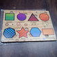 Set of wooden triangle puzzle pieces and the board, highlighting the natural wood material.