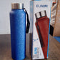 Person carrying black stainless steel water bottle with green cap outdoors