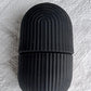 Black face ice roller placed on a textured grey cloth, showing its sleek design.