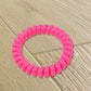 A bulk pack of 100 multi-colored telephone wire hair bands.