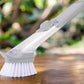 Liquid dispenser dish brush with scraper edge for effective kitchen cleaning.