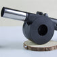 Compact and lightweight hand crank BBQ air blower fan from an angled perspective.
