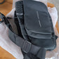 Anti-theft sling bag displayed hanging, featuring secure lock and water-resistant fabric