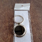 Close-up of round metal keychain with sleek black center and metal rim.
