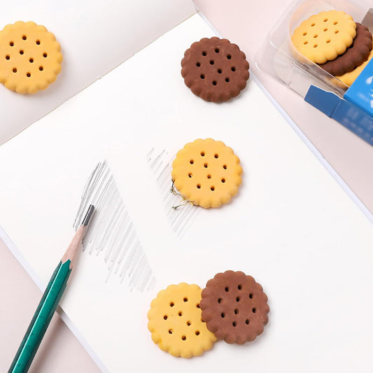 A child's hand holding a fun biscuit eraser next to a pencil, showing usage.